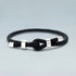 Black braided bracelet with silver knots on a light gray background