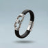 Black braided leather bracelet with silver clasp on a light gray background