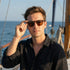 Man wearing sunglasses on a boat with ocean in the background